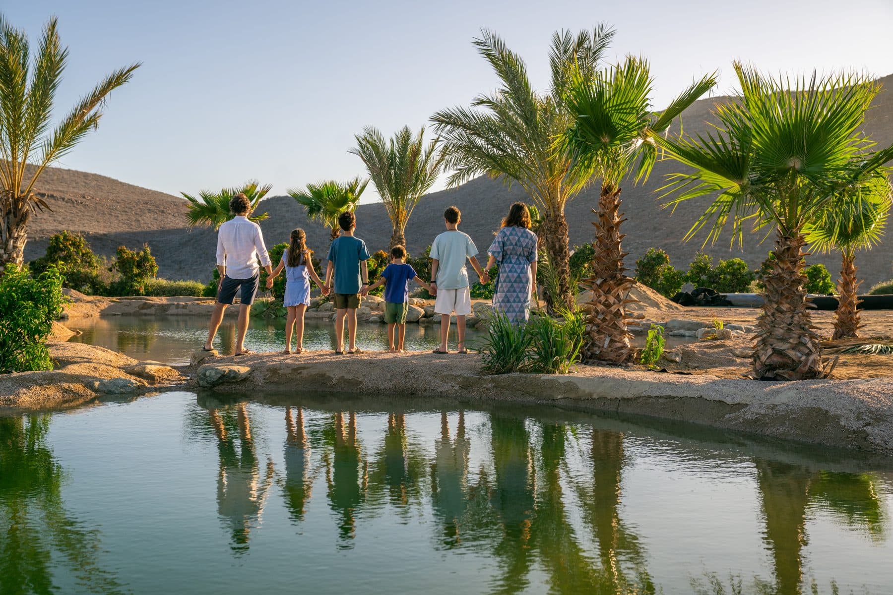 Families gathered at the water's edge at Casa Damara, palms and mountains beyond